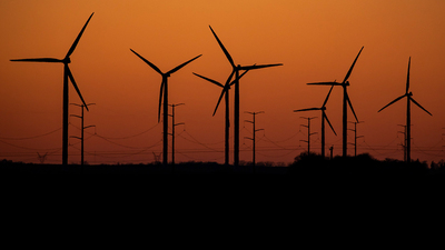 turbines and power poles in the orange sky of early morning light.  Photo by Fred Zwicky