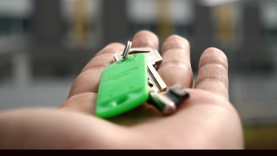 house keys on open palm, housing in background