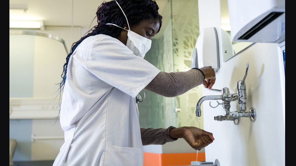 Black medical worker scrubs her hands. Getty Images
