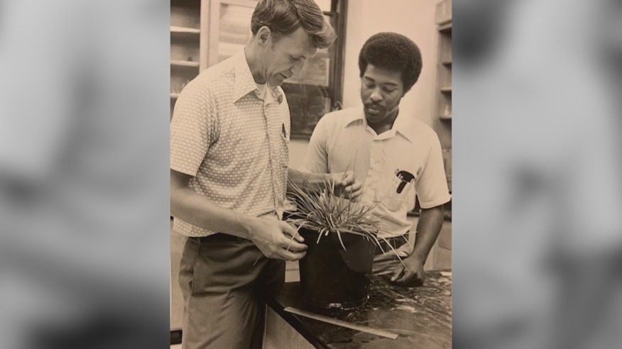Chancellor Jones as a young man examining a plant with a colleague