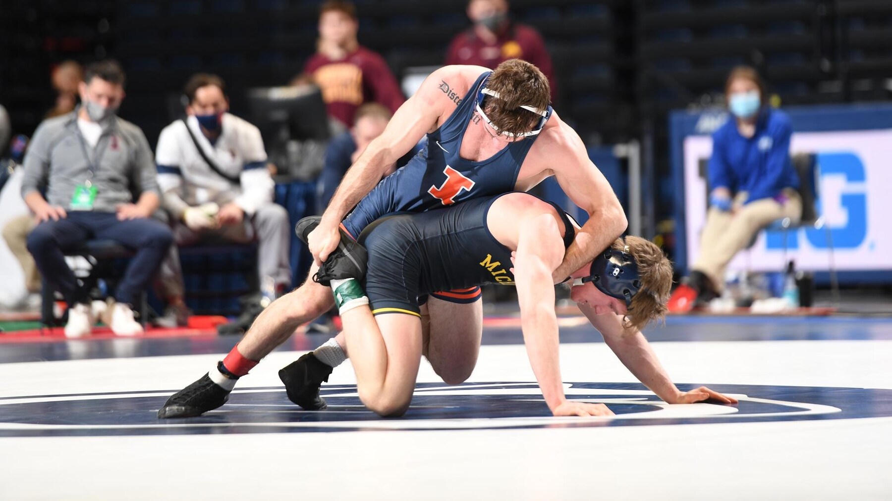 An Illini wrestler grapples with a Michigan wrestler