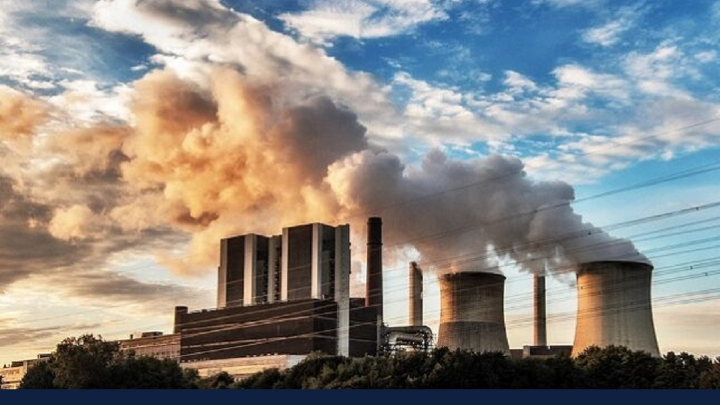 stock picture of a factory emitting pollution into the air. Photo via rawpixel