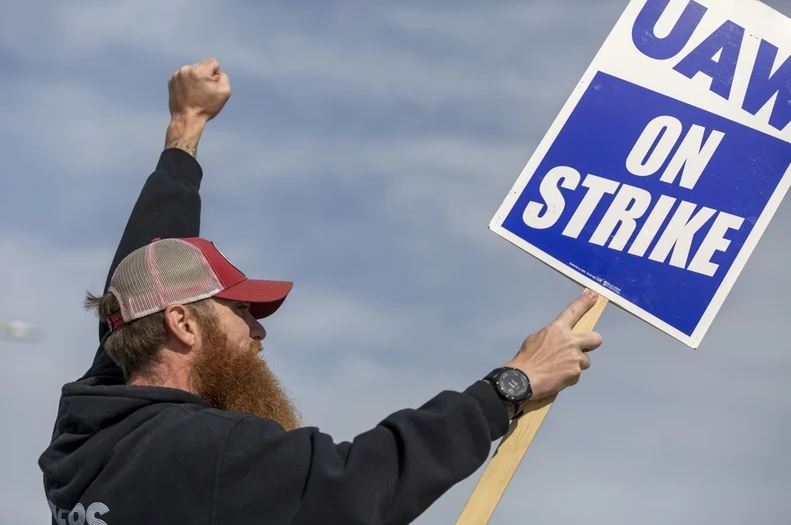 UAW worker carries a sign as he walks the picket link during the strike against John  Deere in East Moline