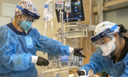 Registered nurse Akiko Gordon, left, and respiratory therapist Janssen Redonado, right, work inside the ICU with a COVID-19 positive patient at Martin Luther King Jr. Community Hospital on Dec. 31, 2021, in Los Angeles. (Francine Orr / TNS)