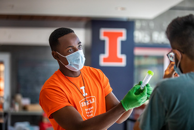 A SHIELD worker explains the protocol for a COVID-19 saliva test at the University of Illinois.