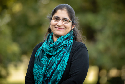 Professor Sumiti Vinayak stands outdoors, wearing a black sweater and a blue scarf.