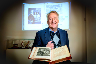 Professor Gregory Girolami with Margaret Bryan's book open in front of him and an image of Bryan and her daughters projected on a screen behind him
