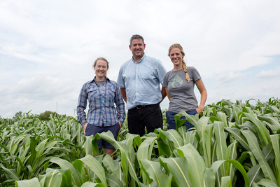 Photo of three researchers standing in a field of sorghum.