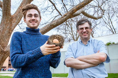 Portrait of the researchers outside. Daniel Clark is holding a nest and egg.