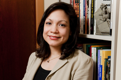 Photo of U. of I. social work professor Lissette Piedra leaning against a bookcase in her office