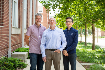 Recreation, sport and tourism professors Jon Welty Peachey, Jules Woolf and Mikihiro Sato and  standing in front of a brick building with trees in the background