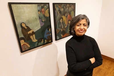 Photo of Nasrin Navab standing in front of her painting on a gallery wall.