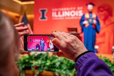 An observer photographs a graduate receiving diploma