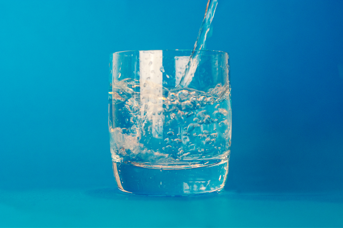 glass of water against a teal background