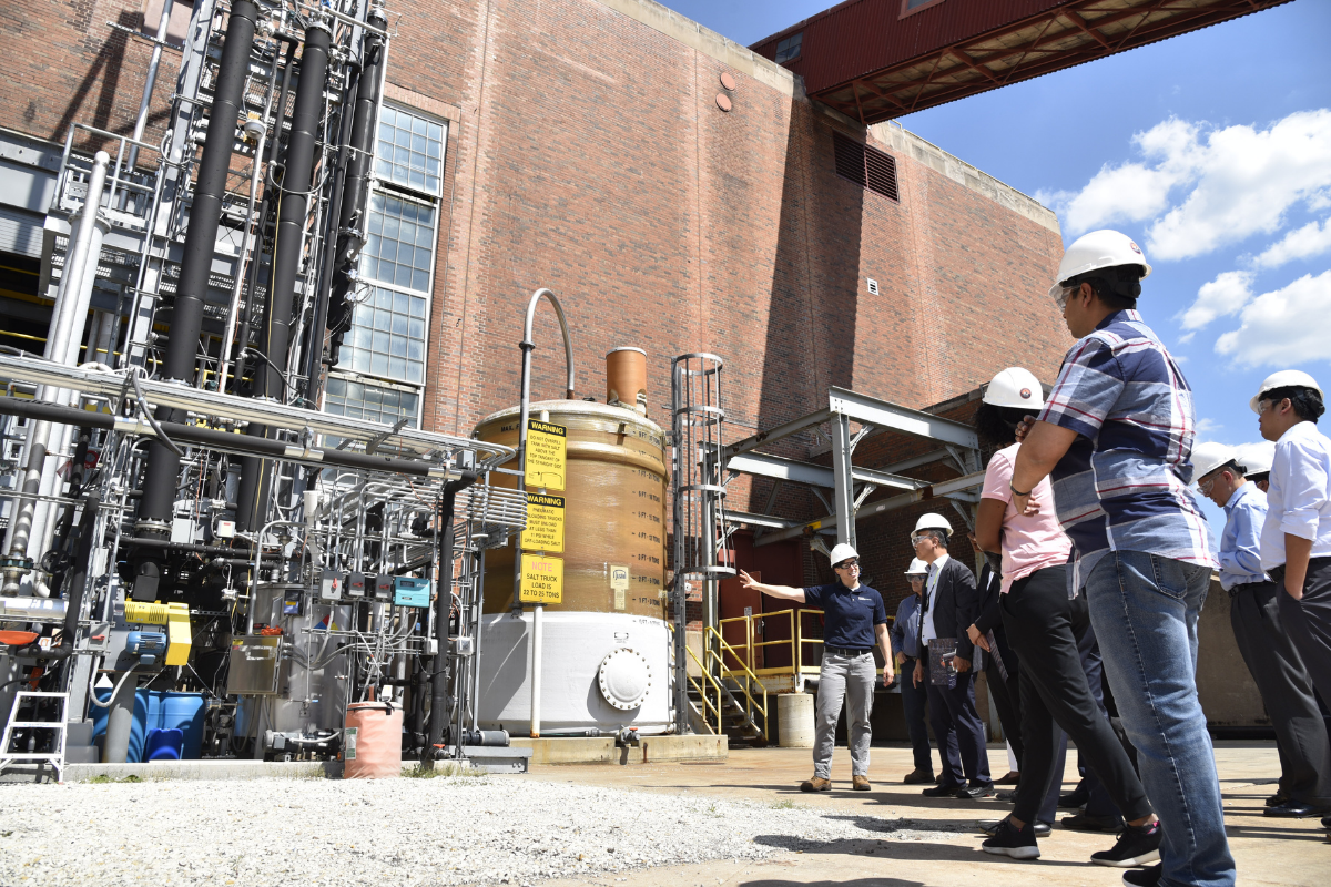 ISTC engineer Stephanie Brownstein gestures toward carbon capture equipment at Abbott Power Plant while speaking to visitors from the Department of Energy and Doosan Corporation