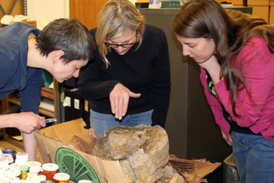 Mary King, Mary Simon, and Kimberly Schaefer examining a possible wooden mortar