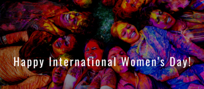 Image of women with colored powder on them for Diwali with text that reads "Happy International Women's Day"