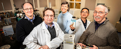 four men and a woman standing in a lab
