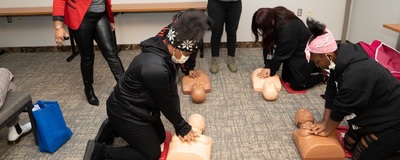 Four young women practice CPR on female and Black and brown mannequins