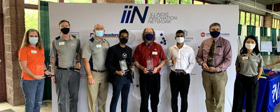 group of masked people holding awards in front of banner