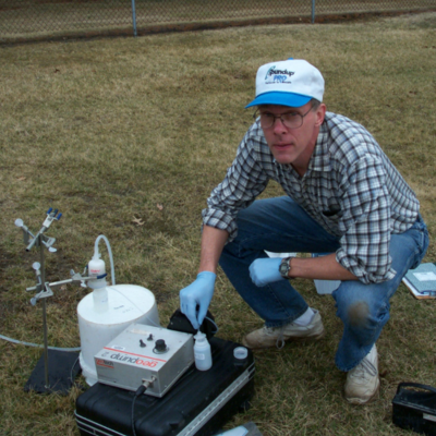 Tom Holm crouches next to water sampling equipment, circa 2002