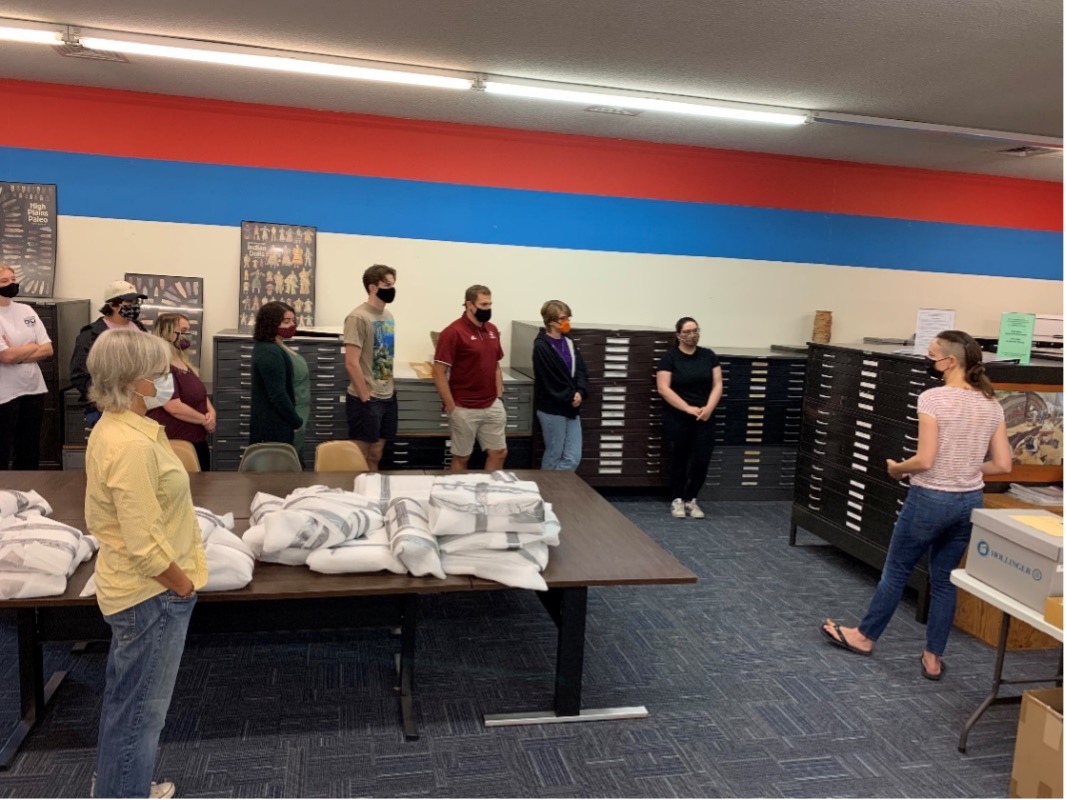 IFR field school director Dr. Brennan (far right) discusses the importance of associated documentation to curation work, such as the large maps stored in the cases they stand in front of.