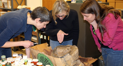 Mary King, Mary Simon, and Kimberly Schaefer examining a possible wooden mortar (large basin for grinding corn).