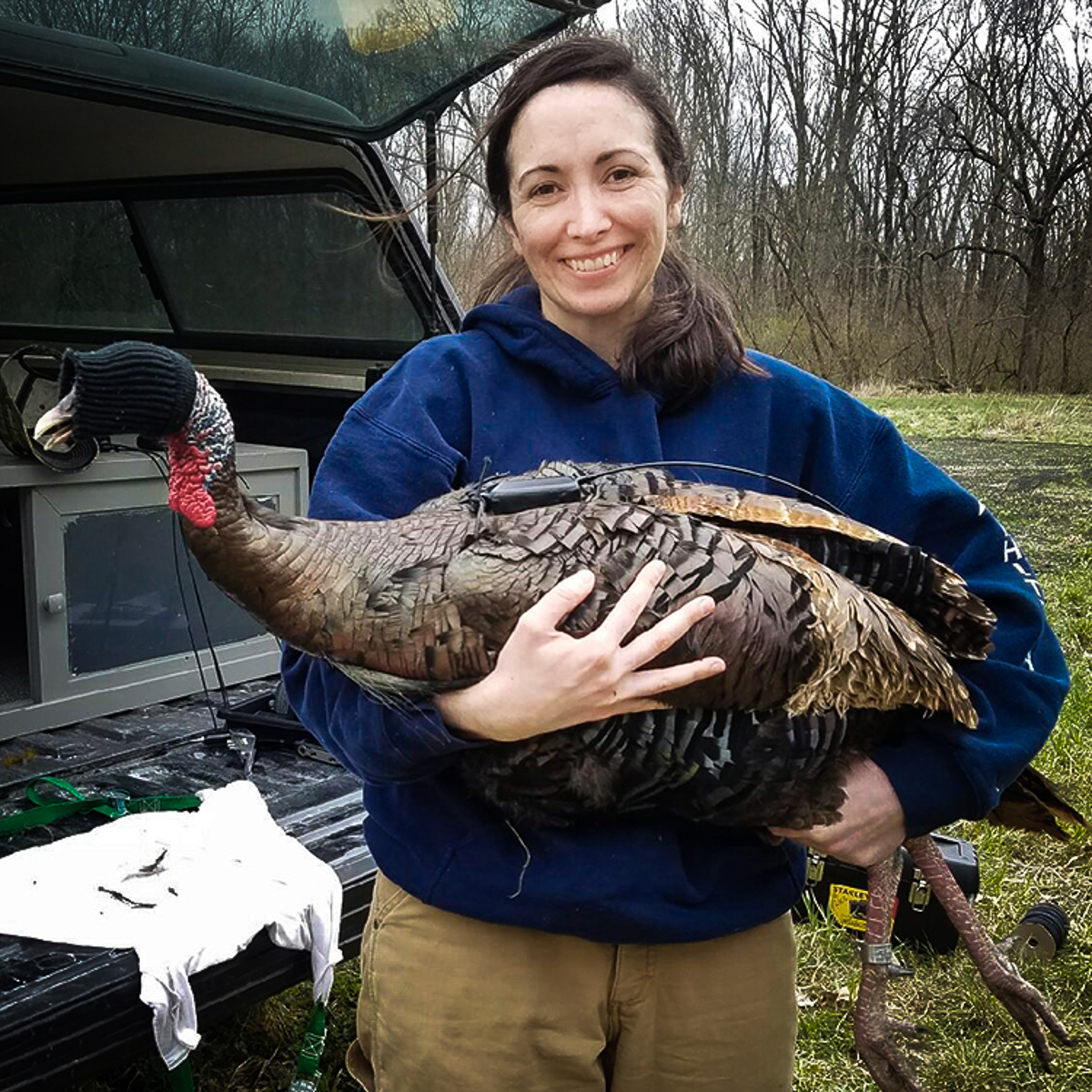 Christine Parker outdoors holding a turkey.