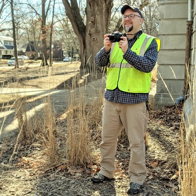 Mike Smith standing and holding a camera.