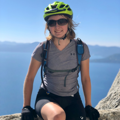 Natalie Kerr leans against a low wall wearing biking gear