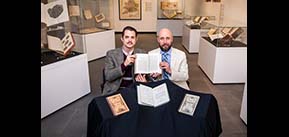 Neal Davis (left) and Ryan Shosted (right) hold a copy of the Book of Mormon written in the Deseret Alphabet at the Rare Book and Manuscript Library.