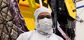 Nanavati in front of the JWST in cleanroom gear