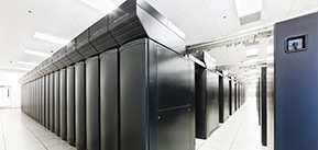 [Image ID: Several banks of supercomputers in a white room, captured at a dramatic angle. End ID]