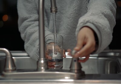 a person drawing water from a home faucet