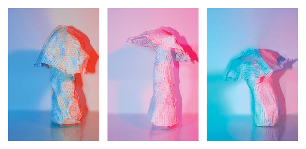 Three paper mushrooms bathed in pink, blue and orange light.