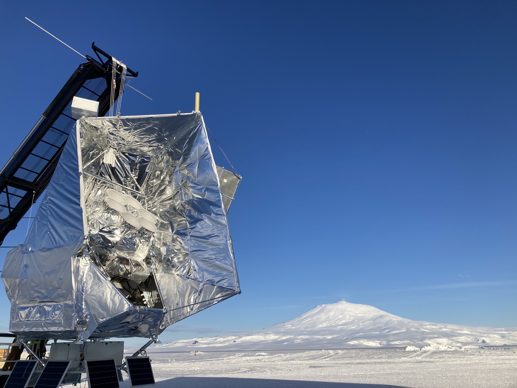 A microwave background telescope sits against a blue sky.